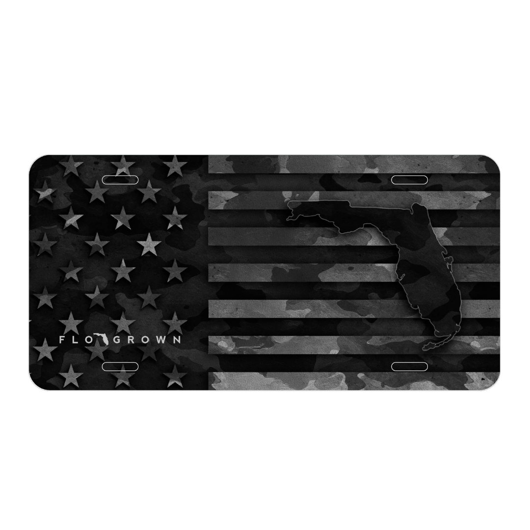 Black and gray camouflage American flag license plate with 'FLO GROWN' branding.