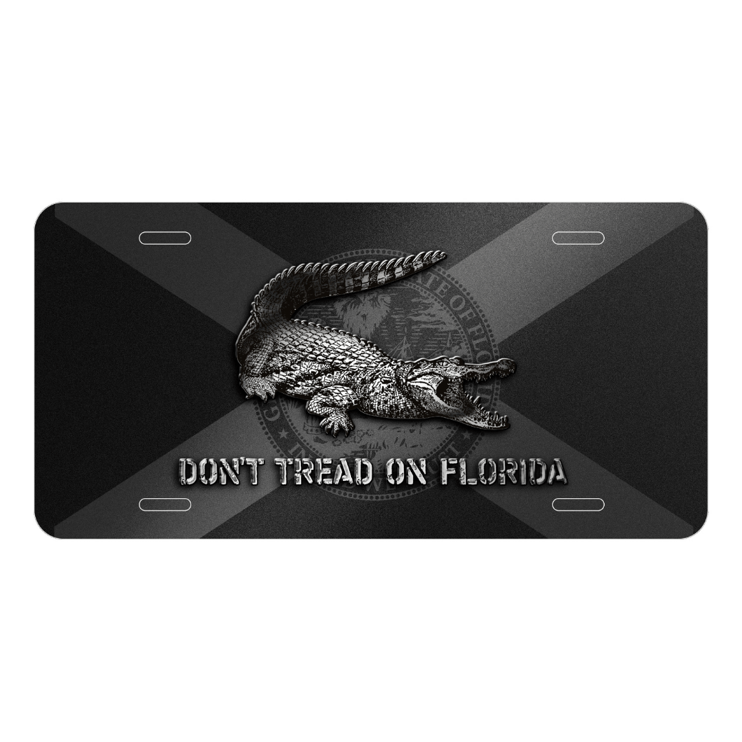 A metal license plate with a sublimated design featuring an alligator and the text 'DON'T TREAD ON FLORIDA', predominantly in black and gray colors with the Florida flag.