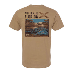 Light brown tee with a graphic of a gator in the swamp and text 'AUTHENTIC FLORIDA' with the Florida flag on the back.