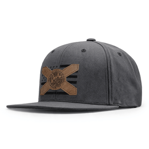 A dark gray textured flat-brim cap featuring a brown leather Florida flag patch with a central circular emblem and a faded black American flag design on the back panel.