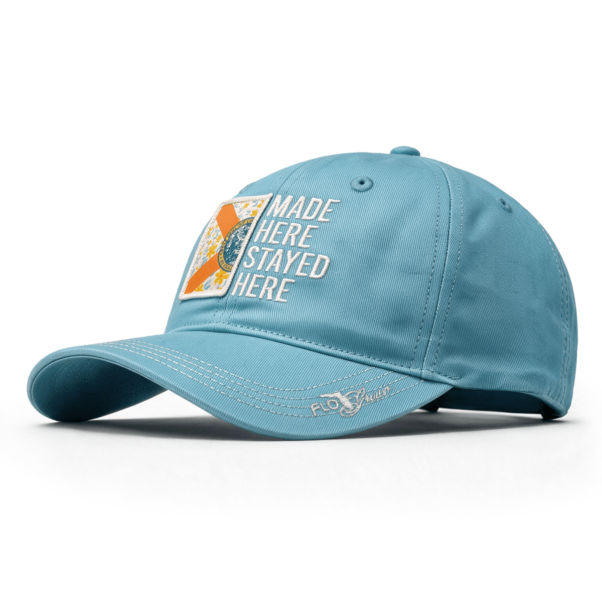 Light blue womens hat with half of a Florida flag on the left side in a floral pattern and the text 'MADE HERE STAYED HERE' on the right side.