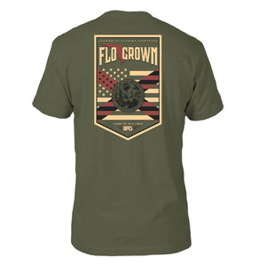 Green tee with a graphic in tan on the back of a crest with the Florida flag over the American flag and the text 'FLOGROWN' at the top.
