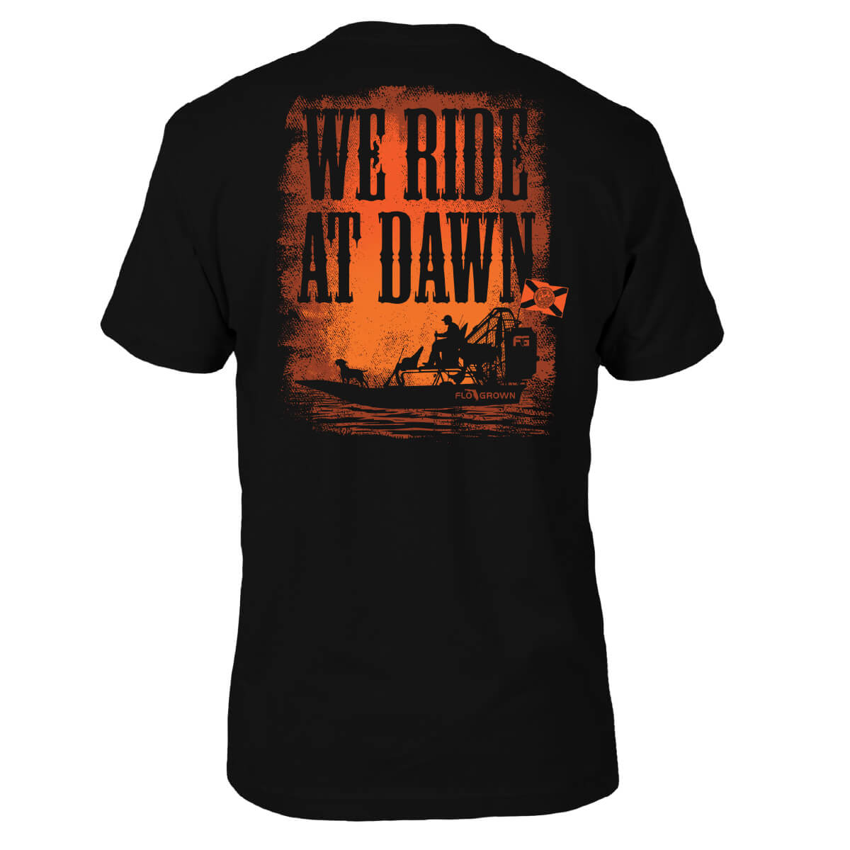 Black tee with a graphic of a man on an airboat with his dog and the text 'WE RIDE AT DAWN' on the back.