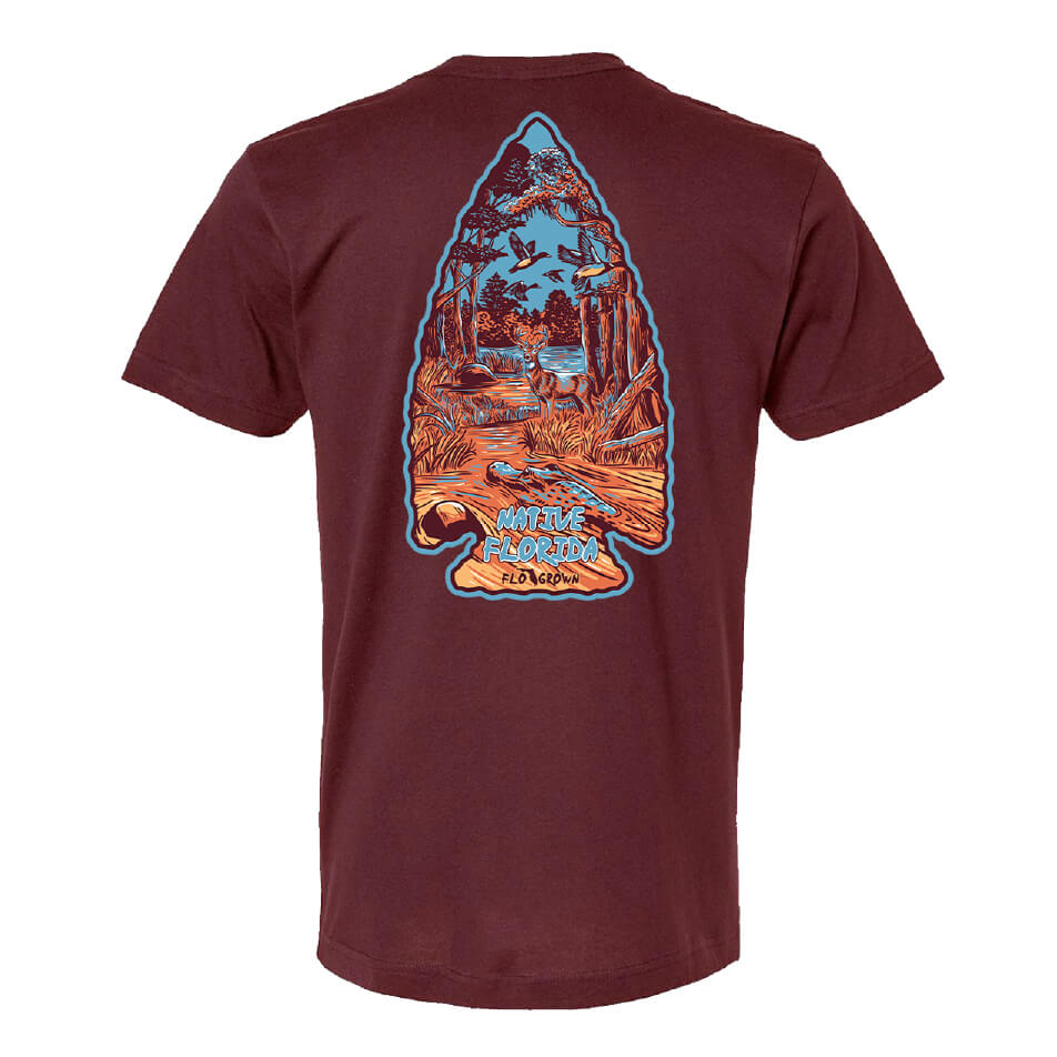 Maroon tee with a graphic of a swamp scene in the shape of an arrowhead on the back.