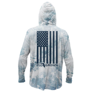 Long sleeve performance hoodie with a design of crashing waves and a vertical American flag on the back.