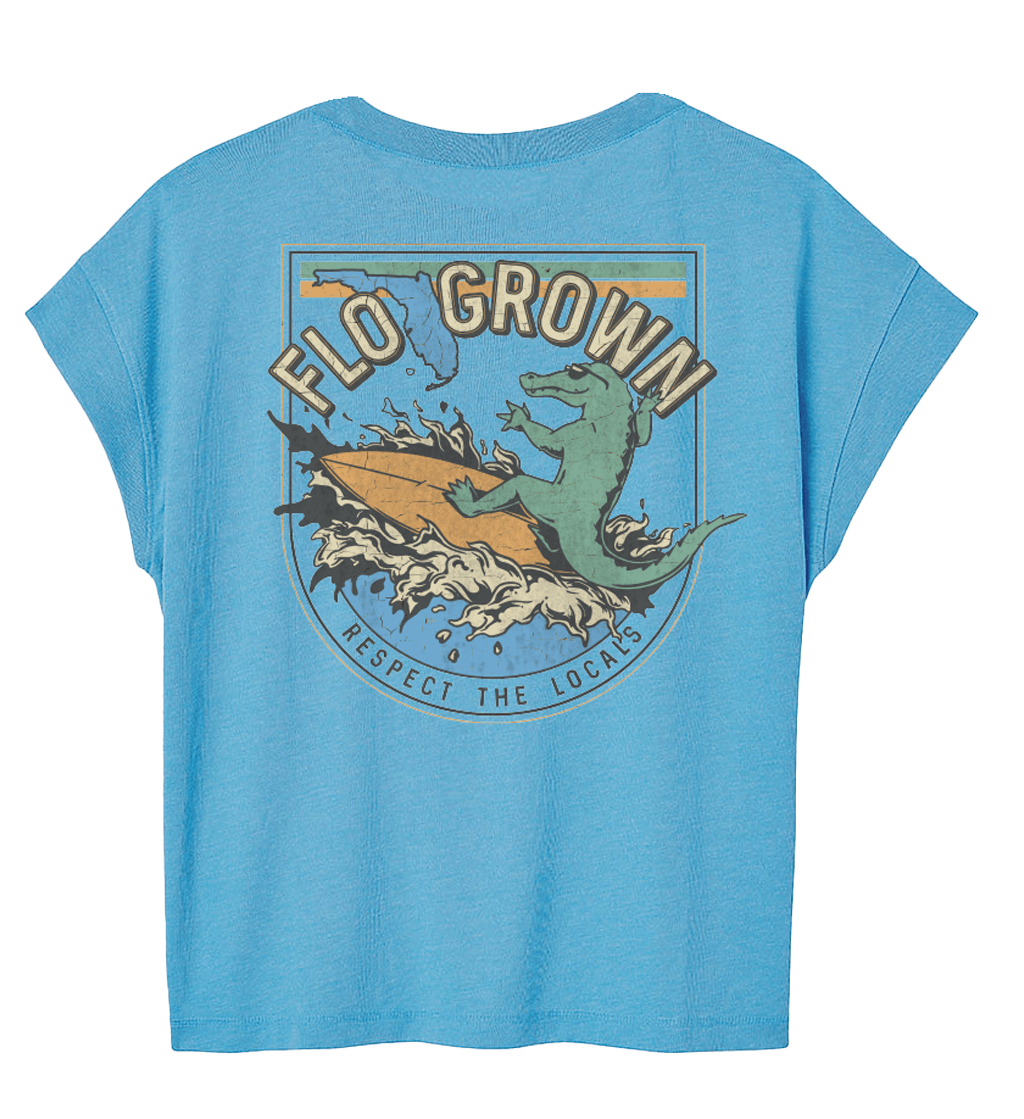 Blue shirt with a gator riding a wave on a surfboard on the back.