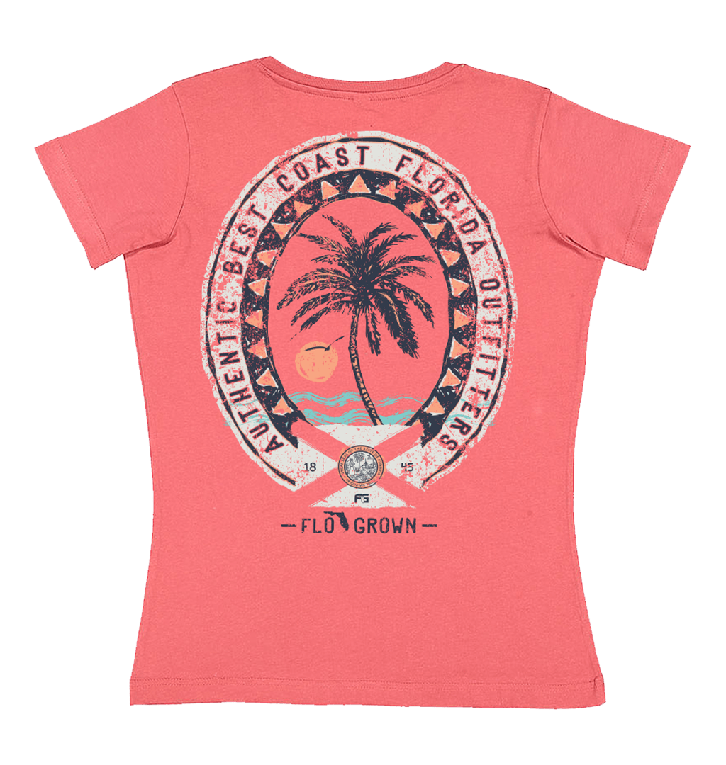 Pink tee with a vintage style graphic of a palm tree on the beach at sunset and an oval crest around it.